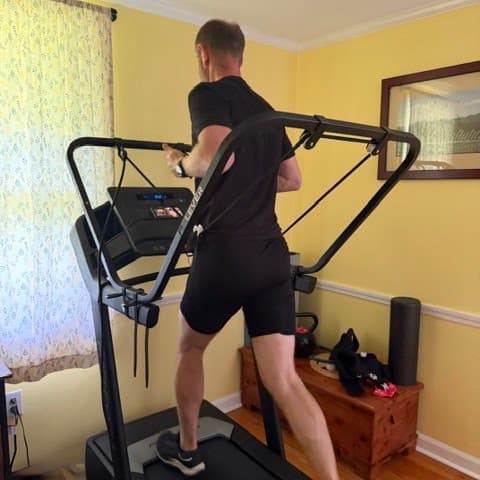 A runner training on a home treadmill with the Lever body-weight support system
